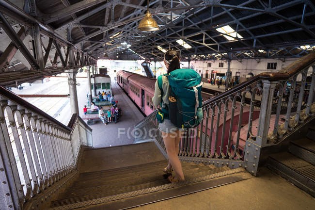 Desde arriba vista trasera de la mujer de vacaciones con la mochila que baja en Colombo estación de tren en Sri Lanka - foto de stock