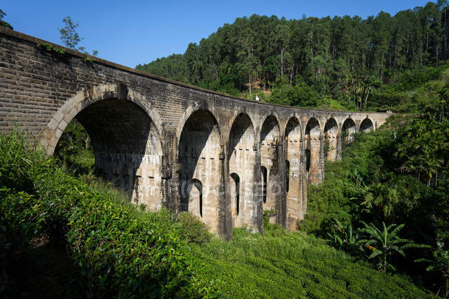 Задумчивая азиатка, идущая по железной дороге по старинному мосту — стоковое фото