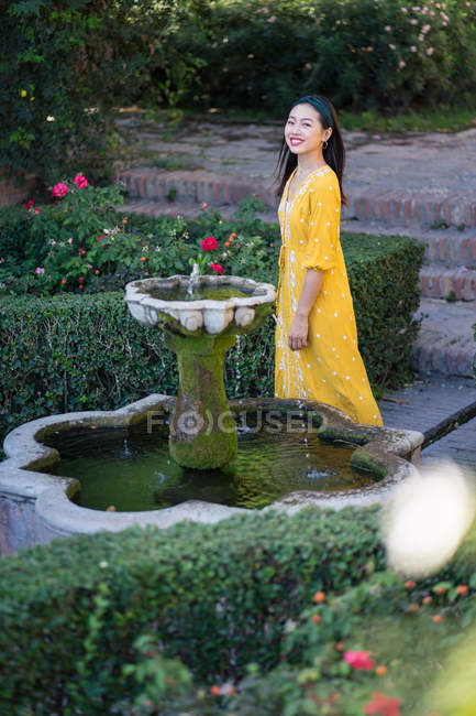 Asiatico donna standing vicino fontana acqua in giardino — Foto stock
