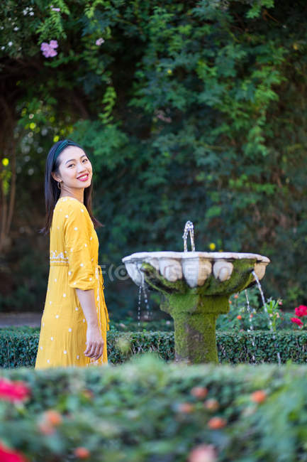 Mulher asiática de pé perto da água da fonte no jardim — Fotografia de Stock