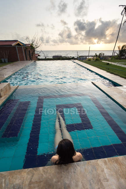 Female traveler in swimsuit resting in pool at resort — Stock Photo
