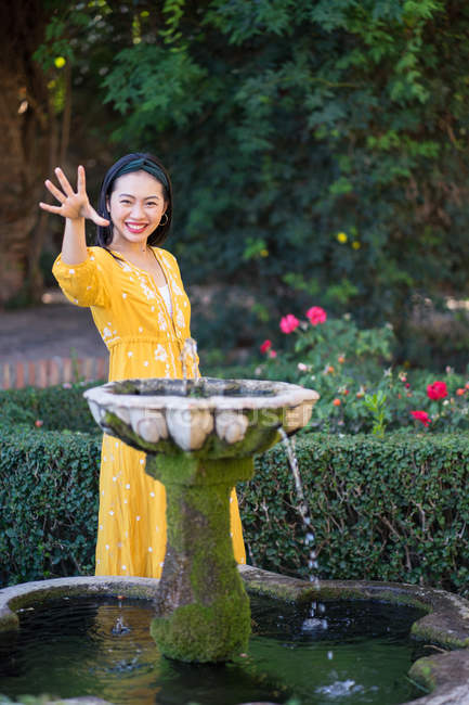 Asiatique femme toucher fontaine eau dans jardin — Photo de stock
