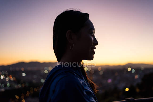 Счастливый азиатский турист против города и заката неба — стоковое фото
