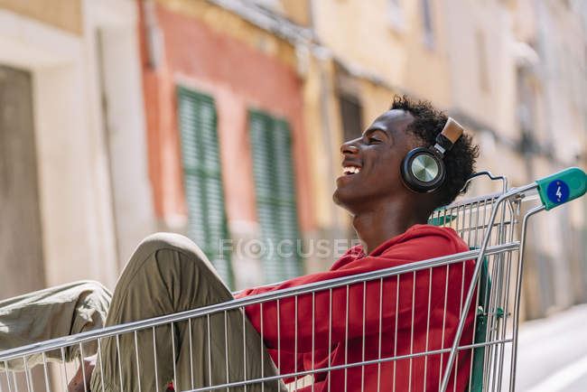 Біля неї можна побачити задумливого підлітка - афроамериканця у звичайному одязі, який дивиться на камеру, сидячи на металевому тролейбусі на вулиці. — стокове фото