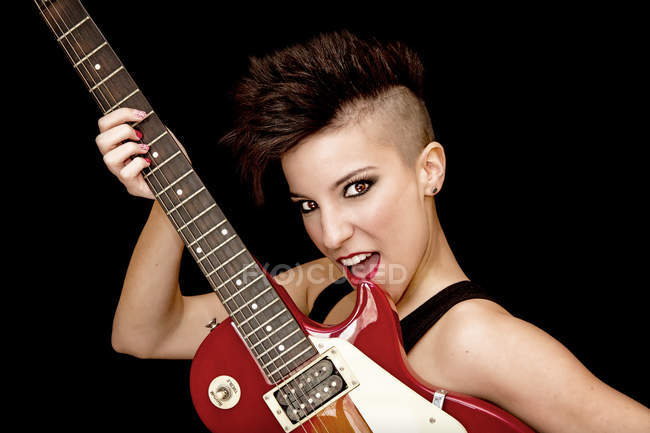 Заколдованная молодая женщина-рокер с электрогитарой в студии — стоковое фото