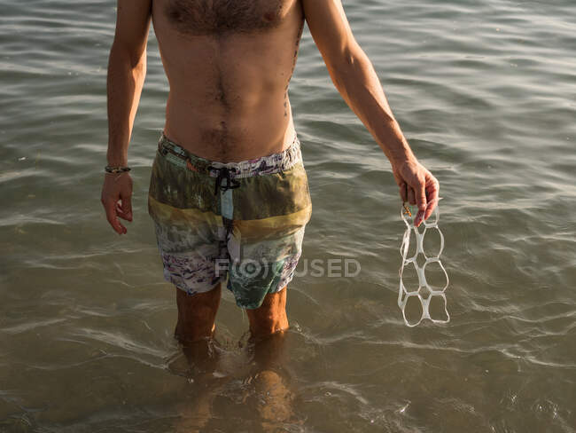 Crop man with plastic garbage in sea — Stock Photo