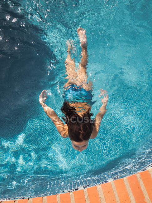 Petite fille nageant dans la piscine — Photo de stock