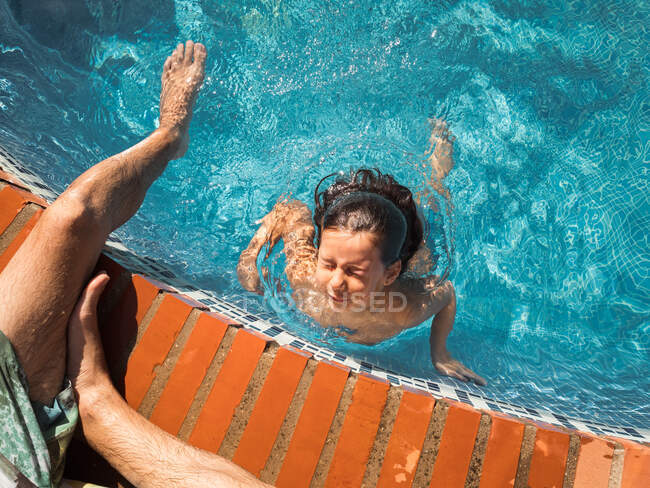 Padre supervisando hija nadando en la piscina - foto de stock