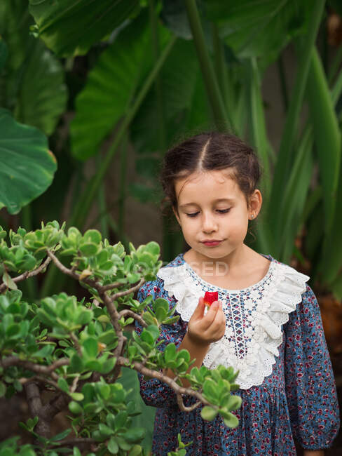 Fille sceptique manger des fruits dans le jardin — Photo de stock