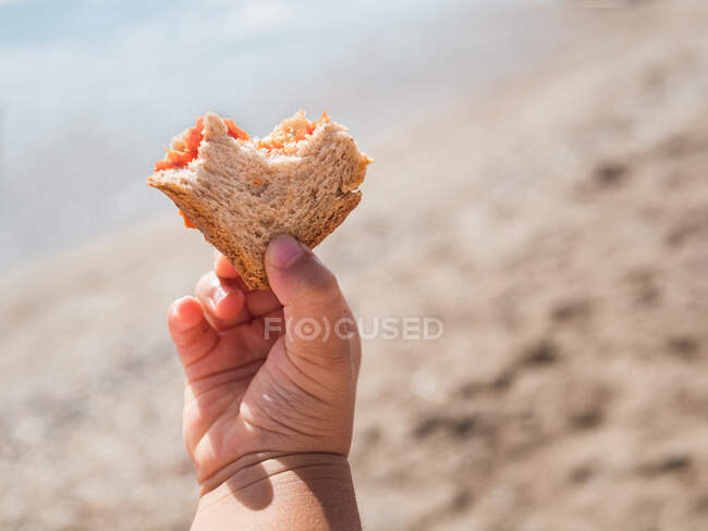 Маленький ребенок держит хлеб на пляже — стоковое фото