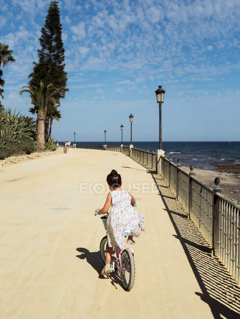 Menina anônima andar de bicicleta no dique — Fotografia de Stock