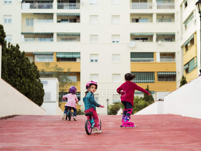 Kids riding bicycles and roller skates together — Stock Photo