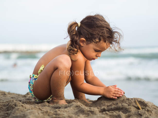 Petite fille construisant château de sable sur la plage — Photo de stock