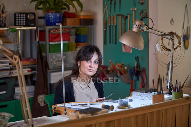 Schöne Kunsthandwerker Juwelierin arbeitet in einem Schmuckgeschäft mit Werkzeugen und einer Glühbirne — Stockfoto