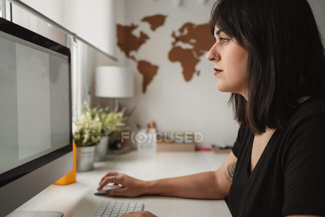 Empresaria enfocada usando computadora de escritorio en la oficina - foto de stock