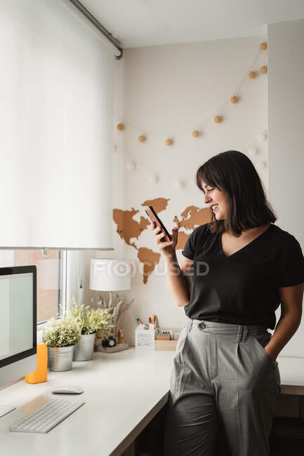 Mulher focada com mensagens de cabelo escuro no celular ao ser — Fotografia de Stock