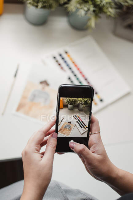 Pintora feminina irreconhecível tirando fotos em smartphones no trabalho — Fotografia de Stock