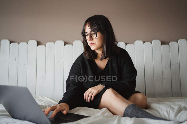 Орієнтована молода студентка використовує ноутбук на ліжку вдома — стокове фото