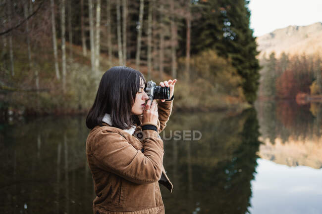 Mujer tomando fotos a orillas del lago - foto de stock