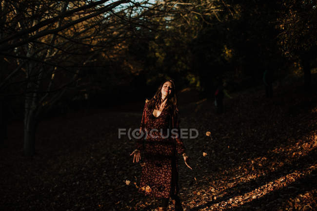 Mulher satisfeita em uso casual dançando em um parque cheio de folhas de outono e sorrindo — Fotografia de Stock