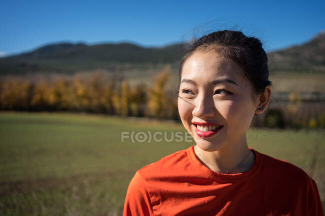 Посміхнена азіатка ходить по сільському полю. — стокове фото