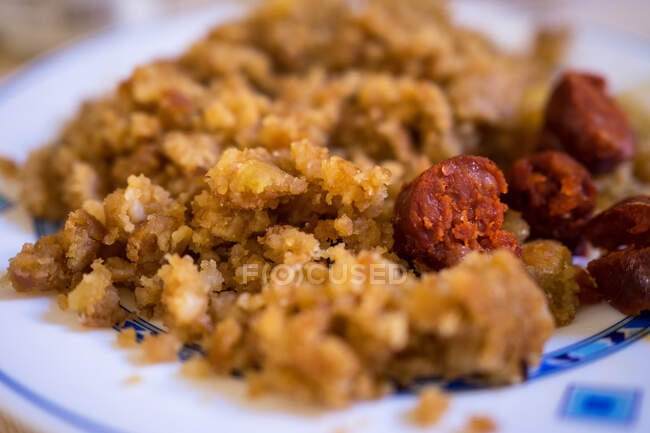 Tasty crumbs with sausage on ornamental plate on table — Stock Photo