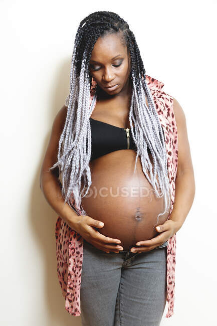 Feliz mujer embarazada afroamericana cogida de la mano en el vientre - foto de stock