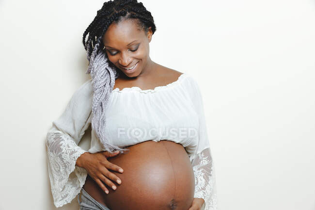 Heureuse femme enceinte afro-américaine tenant la main sur le ventre — Photo de stock