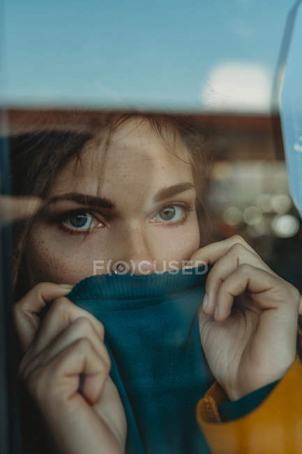 Pensive jeune femme triste avec dreadlocks appuyé contre le verre de fenêtre et détournant les yeux — Photo de stock