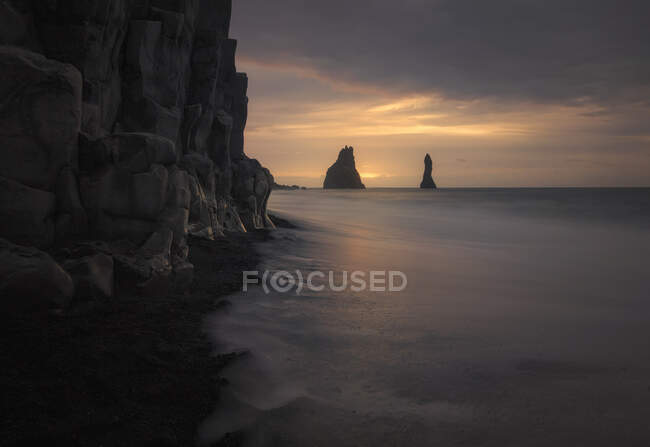 Célèbre plage de sable noir insolite et littoral rocheux au coucher du soleil en Islande — Photo de stock