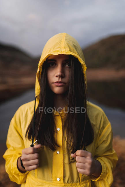 Viajante em capa de chuva amarela em pé na costa do lago — Fotografia de Stock