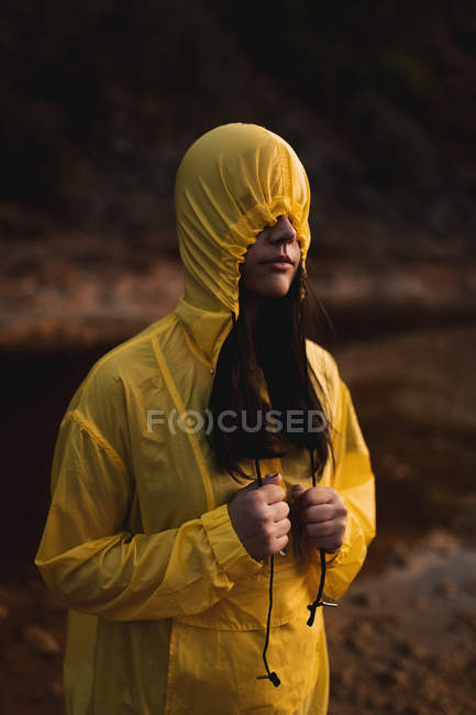 Mulher em capa de chuva amarela passeando na natureza — Fotografia de Stock