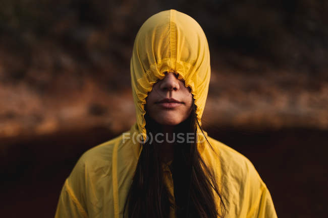 Жінка в жовтому плащі, що йде в природі — стокове фото
