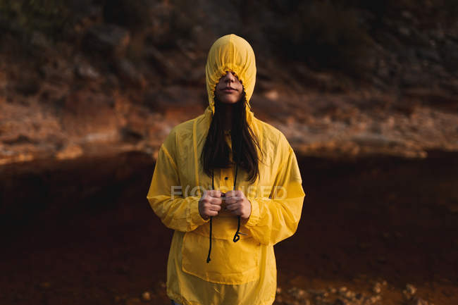 Femme en imperméable jaune flânant dans la nature — Photo de stock