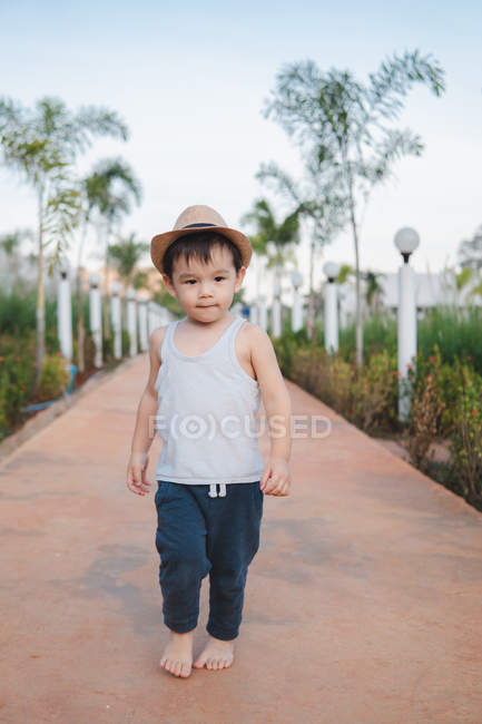 Asian kid walking barefoot in street — Stock Photo