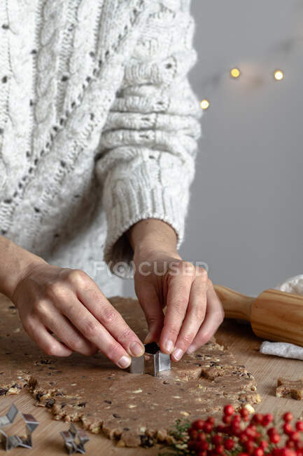 Mãos de colheita de mulher sem rosto fazendo biscoitos de gengibre com forma de lata em forma de estrela na cozinha — Fotografia de Stock