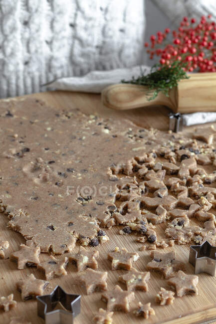 Dall'alto di pasta fatta rotolare marrone su tavolo per biscotti in forma di stella in cucina — Foto stock