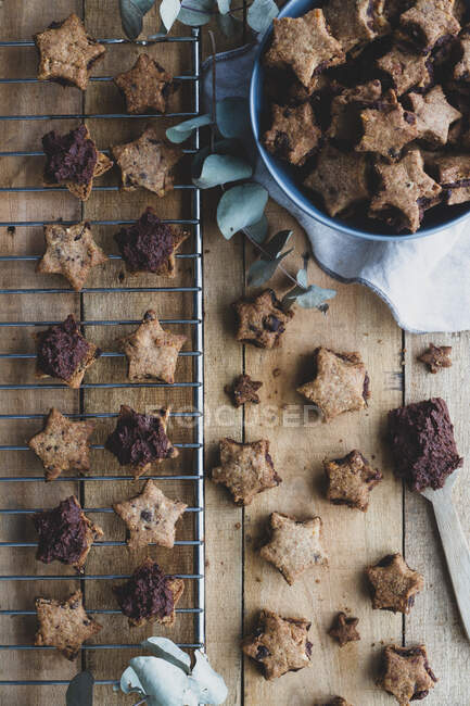 Top view of pieces of cookies on grill from oven with spoon of chocolate for finished cookies on wooden table in kitchen — Stock Photo