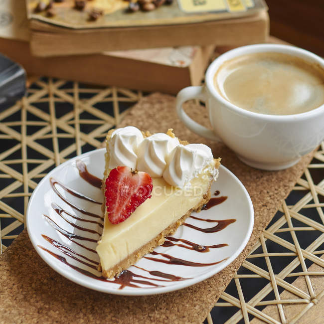 De cima da placa com delicioso cheesecake com morango e creme perto da xícara de cappuccino na mesa — Fotografia de Stock