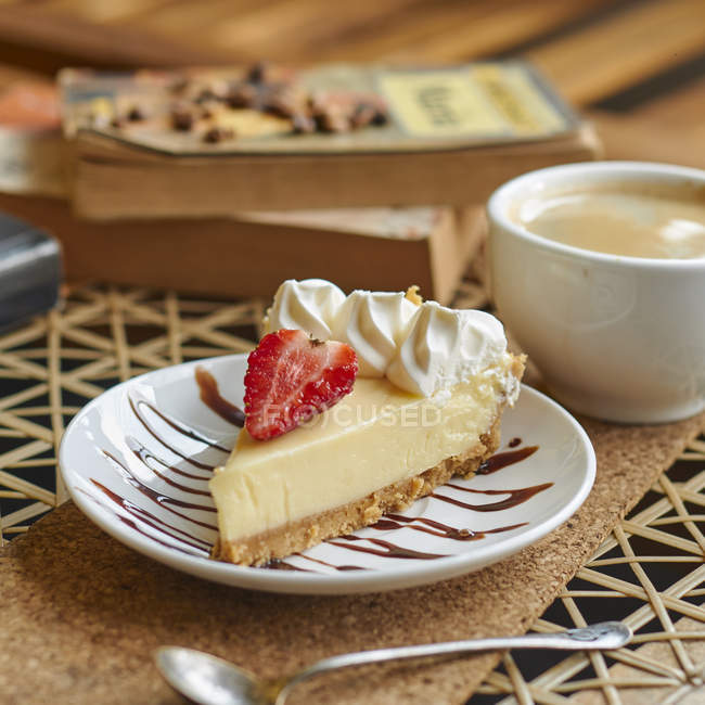 Desde arriba de la plato con deliciosos quesecake con fresa y crema cerca de la taza de cappuccino en la mesa. - foto de stock