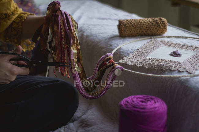 Abgeschnittenes Bild einer Frau, die einen handgefertigten Traumfänger mit langen Fäden erschafft, der Zeit im Haus verbringt — Stockfoto