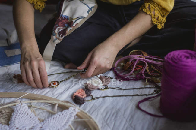 Immagine ritagliata della donna creando dreamcatcher fatto a mano con fili lunghi e accessori seduti in casa — Foto stock