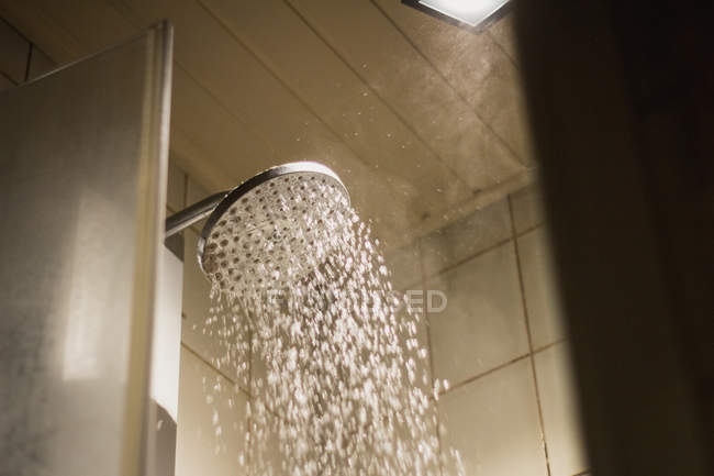 From below of shower head with hot water drops flowing in bathroom of modern house — Photo de stock