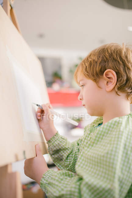 Ребенок рисует на холсте дома — стоковое фото