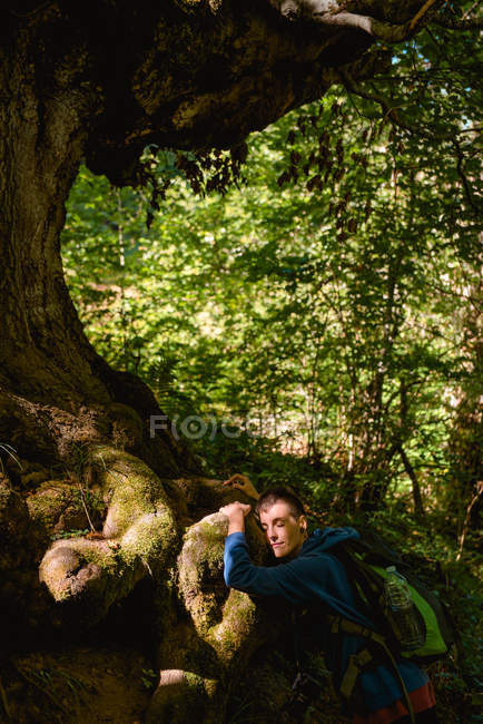 Peaceful young woman in casual clothes enjoying nature hugging a old tree trunk in forest — Stock Photo
