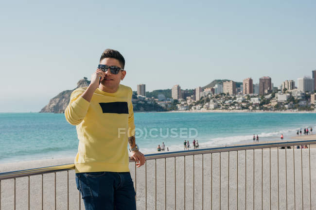 Contenuto viaggiatore maschile che chiama su smartphone sul lungomare — Foto stock