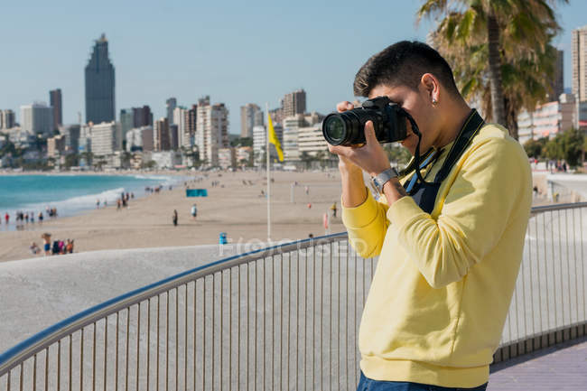 Creativo joven fotógrafo de tiro en la costa - foto de stock