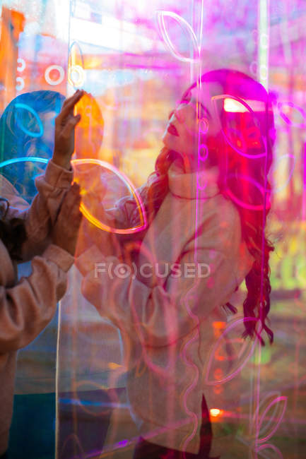 Junge Frau entspannt sich im Licht von Leuchtreklamen mit Reflexion auf der Stadtstraße — Stockfoto
