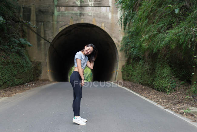 Side view of Asian woman laughing at camera with rocked tunnel among green plants on background at Taiwan — Stock Photo