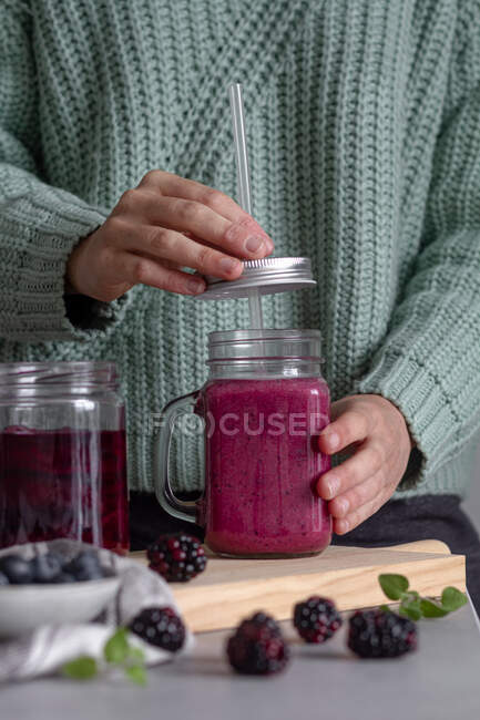 Человек, держащий стеклянный кувшин вкусного ягодного смузи — стоковое фото
